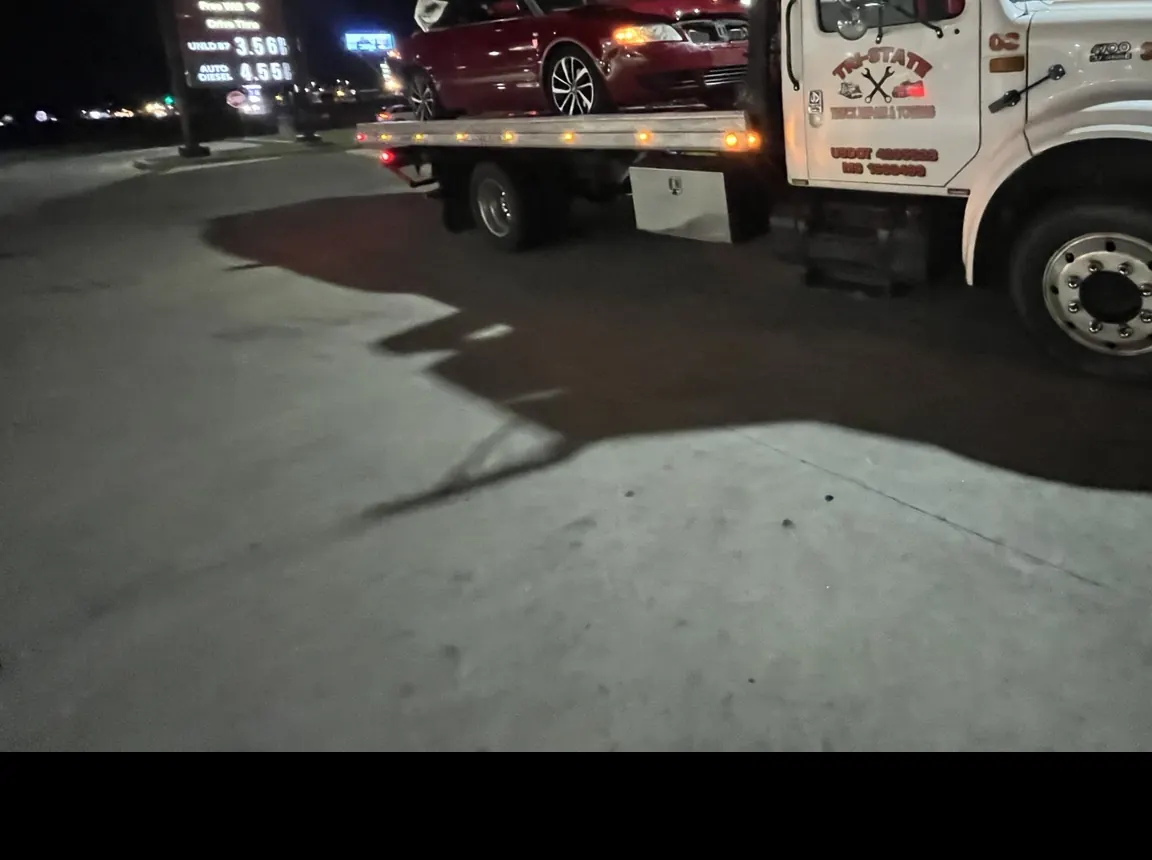 Tri-State International rollback towing a vehicle at night